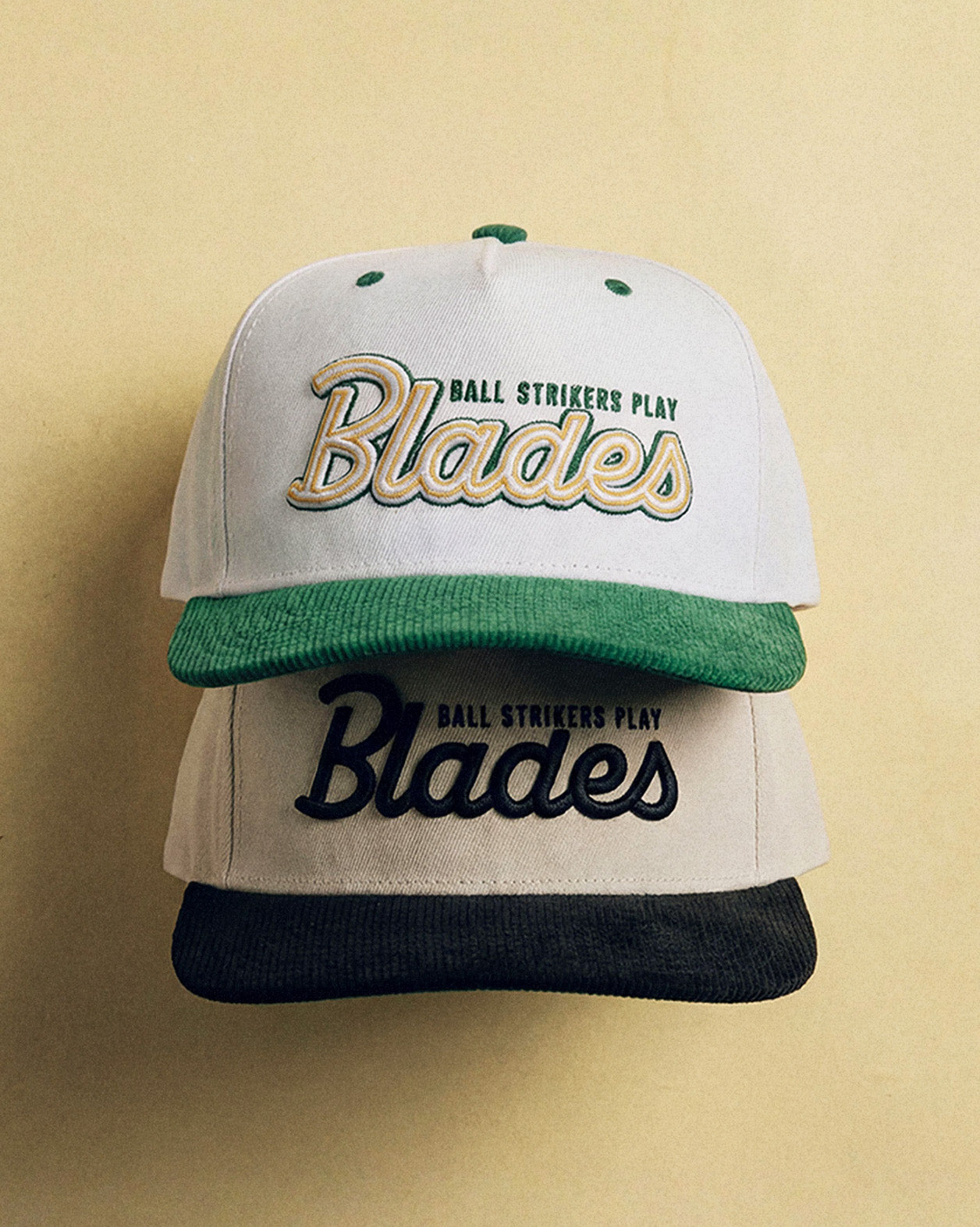 Two baseball caps with 'Blades' branding on a beige background